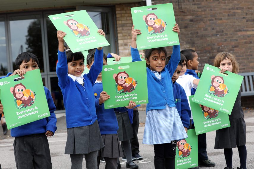 Children holding up Little Monkey by Marta Altes at Elmhurst primary school in Newham
